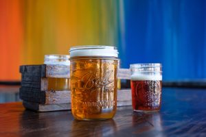 Several pints of beer with a colorful wall in background