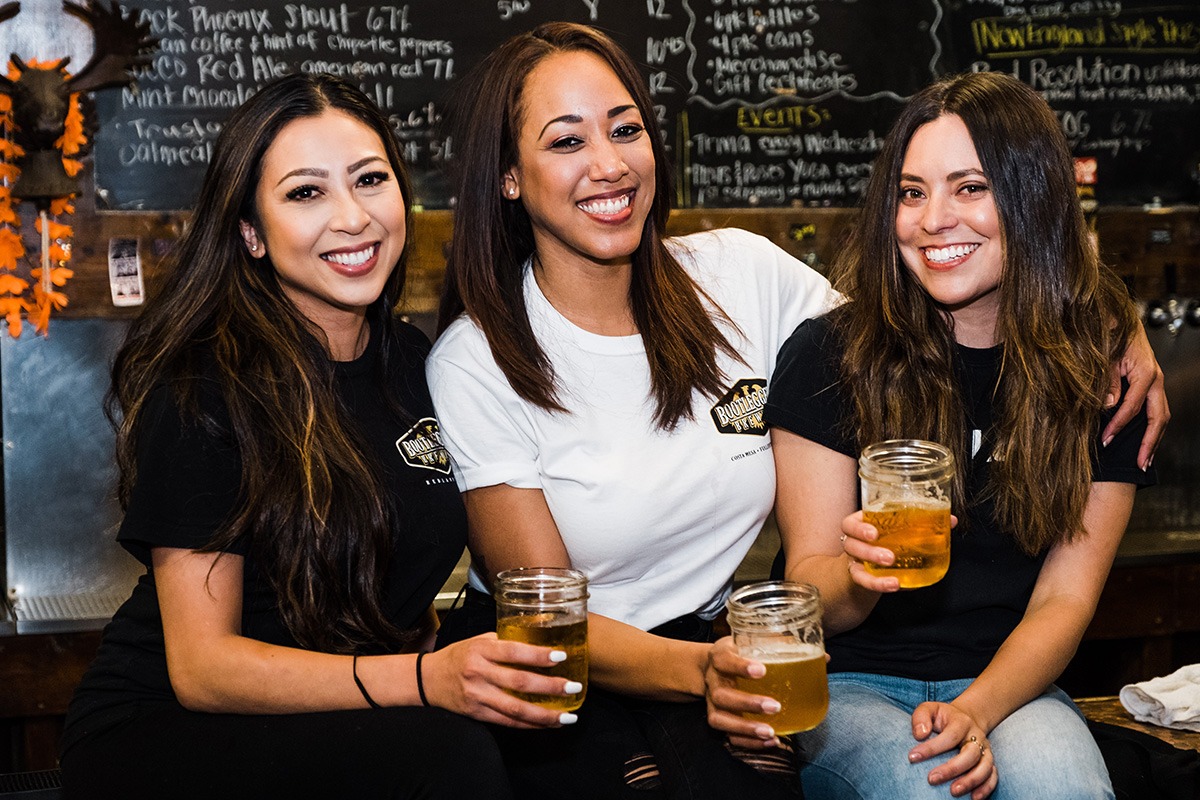 Three smiling ladies enjoying beers in bootlegger's shirts