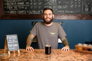 Smiling beertender with a beer on the counter